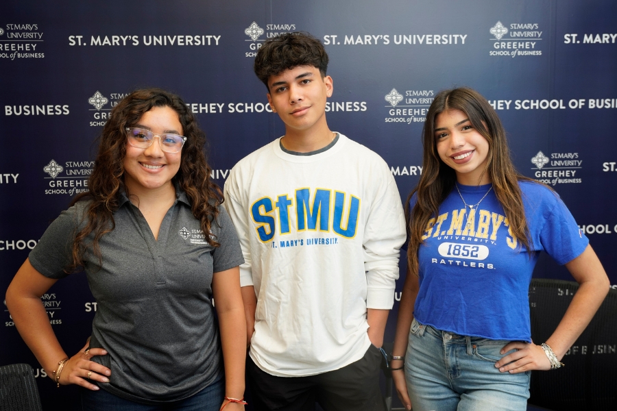 Three GSB students pose in front of a business school backdrop.