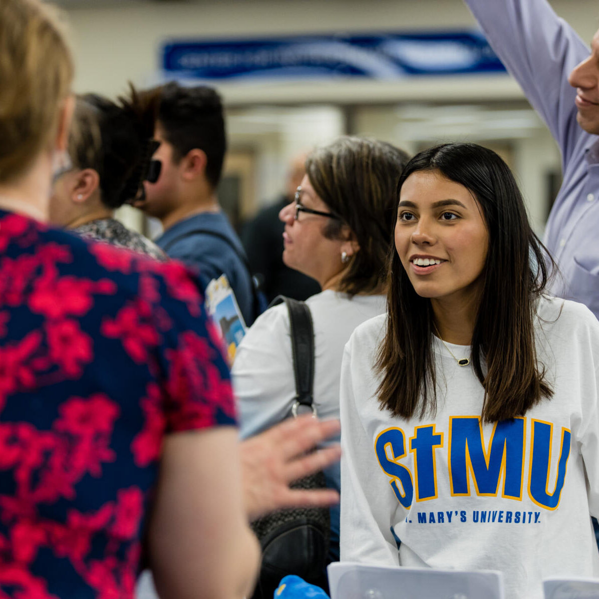 Female student wearing a St. Mary's University excitedly meets St. Mary's staff as they assist her.