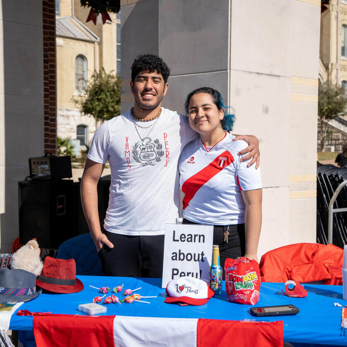 International students during International Education Week pose by a table teaching about Peru