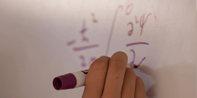 Hand using a dry erase maker to write on a white board.