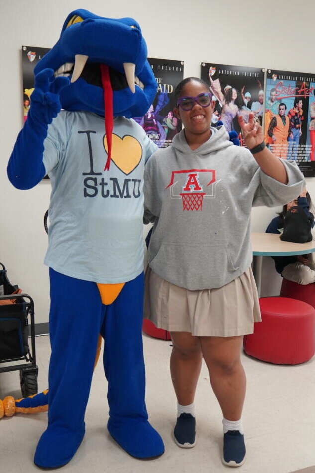 A female high school student from Antonian takes a photo with St. Mary's University mascot, Rattler Man.