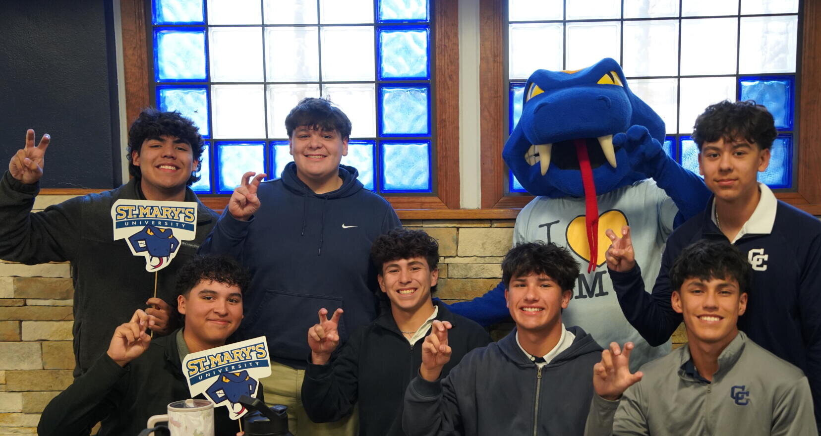 A group of high school boys at Central Catholic show their St. Mary's pride with the hand gesture "Fangs Out" as they take a photo with St. Mary's University mascot, Rattler Man.