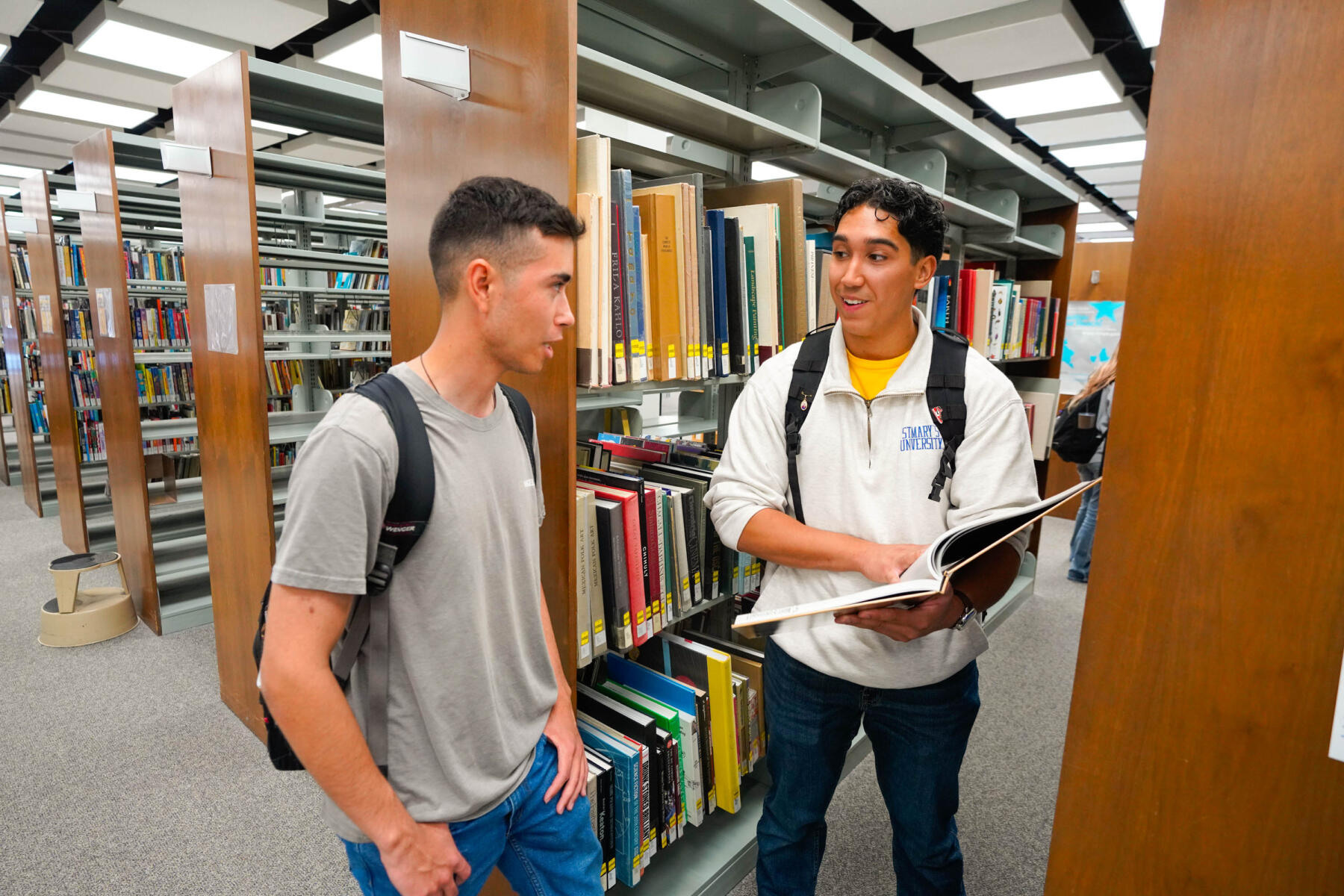 Students in the library look at books.