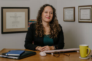 Andrea Beleno Harrington, J.D., sits at her desk in her office in the Center for Legal and Social Justice building.