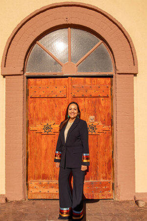 Christine Serrano (B.B.A. ’95, M.B.A. ’99) in front of church door at Ysleta del Sur Pueblo.