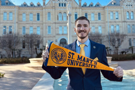 Robbie Breslin holds a 91TV's University pennant in front of St. Louis Hall.