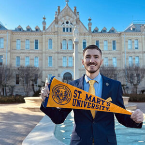 Robbie Breslin holds a ������Ƶ's University pennant in front of St. Louis Hall.