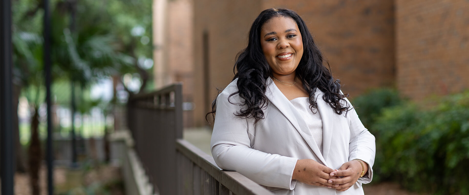 Portrait of Jordyn Roberts in a light lavender suit standing outside on School of Law campus.