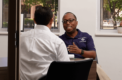 Two people sitting in an office conversing with eachother.