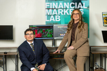 In the Albert B. Alkek Business Building, Professor Violeta Díaz, Ph.D., right, and Richard J. Rodriguez (B.B.A. ’26) review market data via the Bloomberg Terminal.