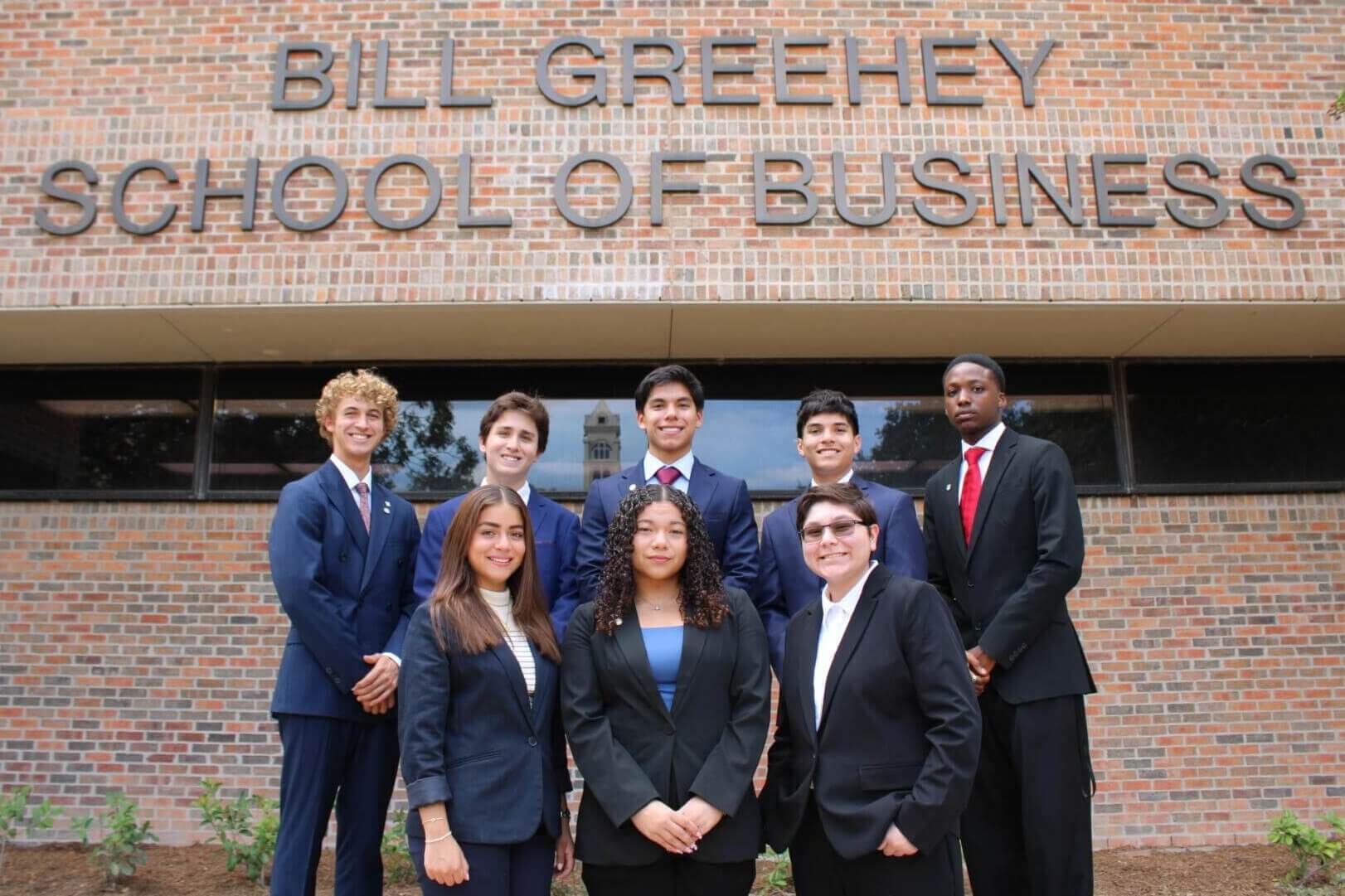 Greehey Scholars in front of the Bill Greehey School of Business sign.