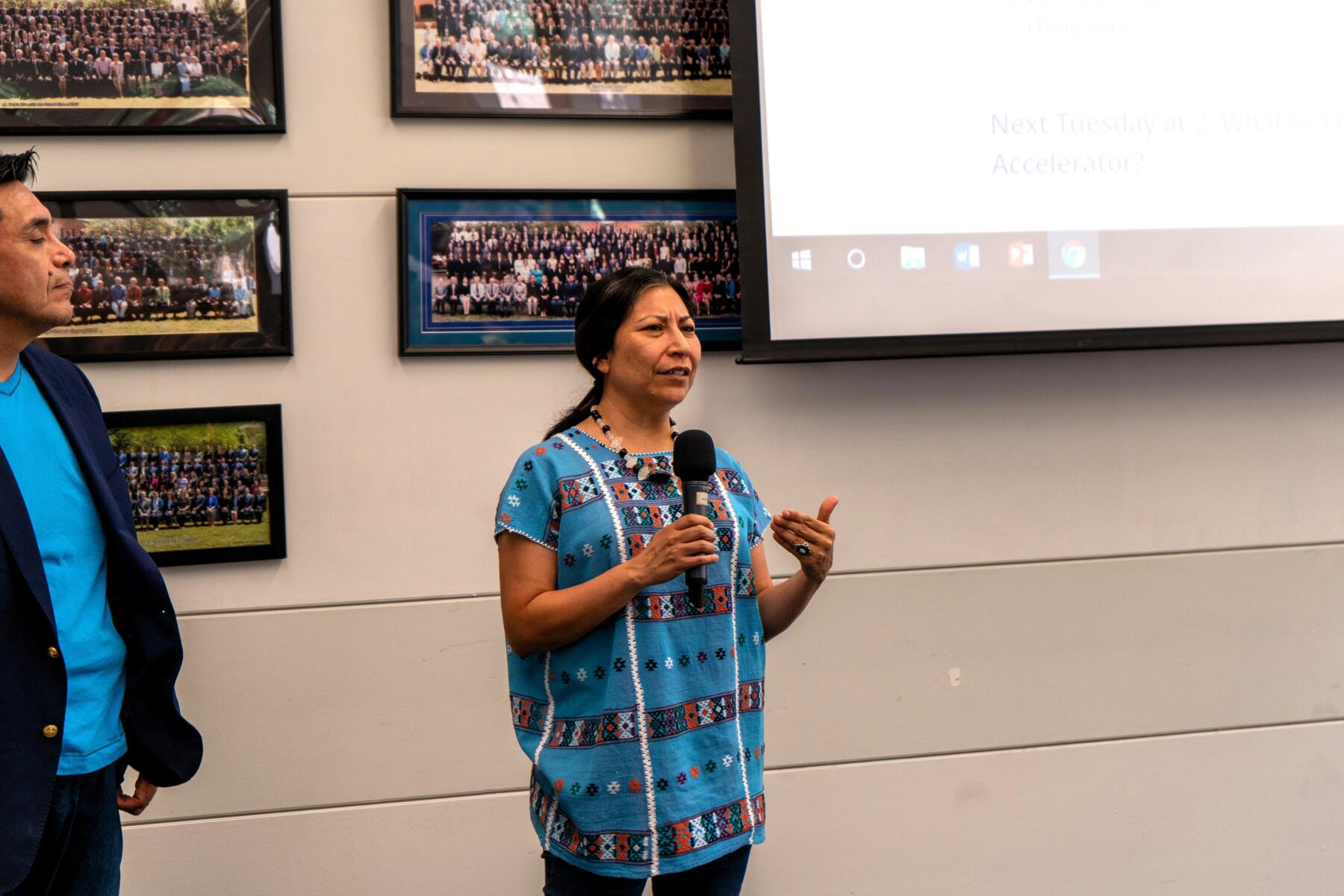 Female wearing traditional clothing giving a presentation.