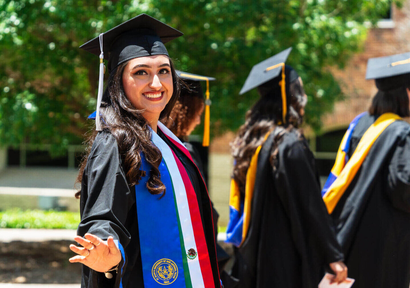Female student smiles proudly wearing her regalia.