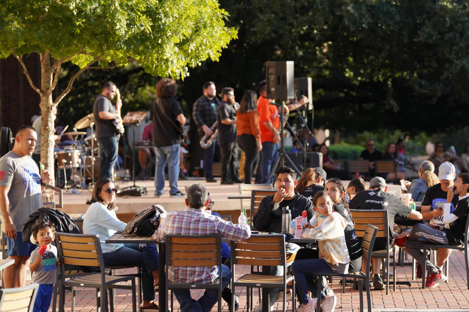 Families sit together outside while listening to live music.