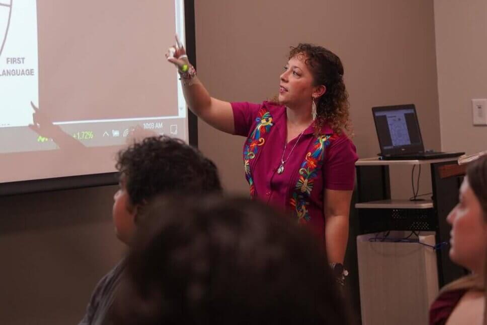 A female presenter points to a slide on her presentation.
