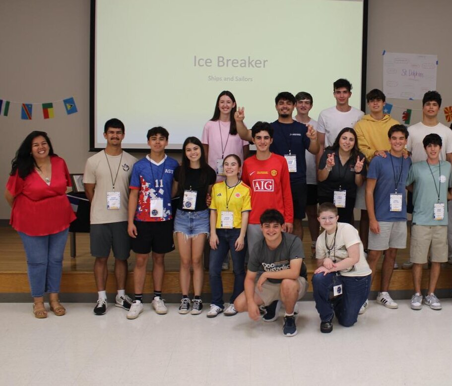 A group of people gather in the front of the classroom for a photo.